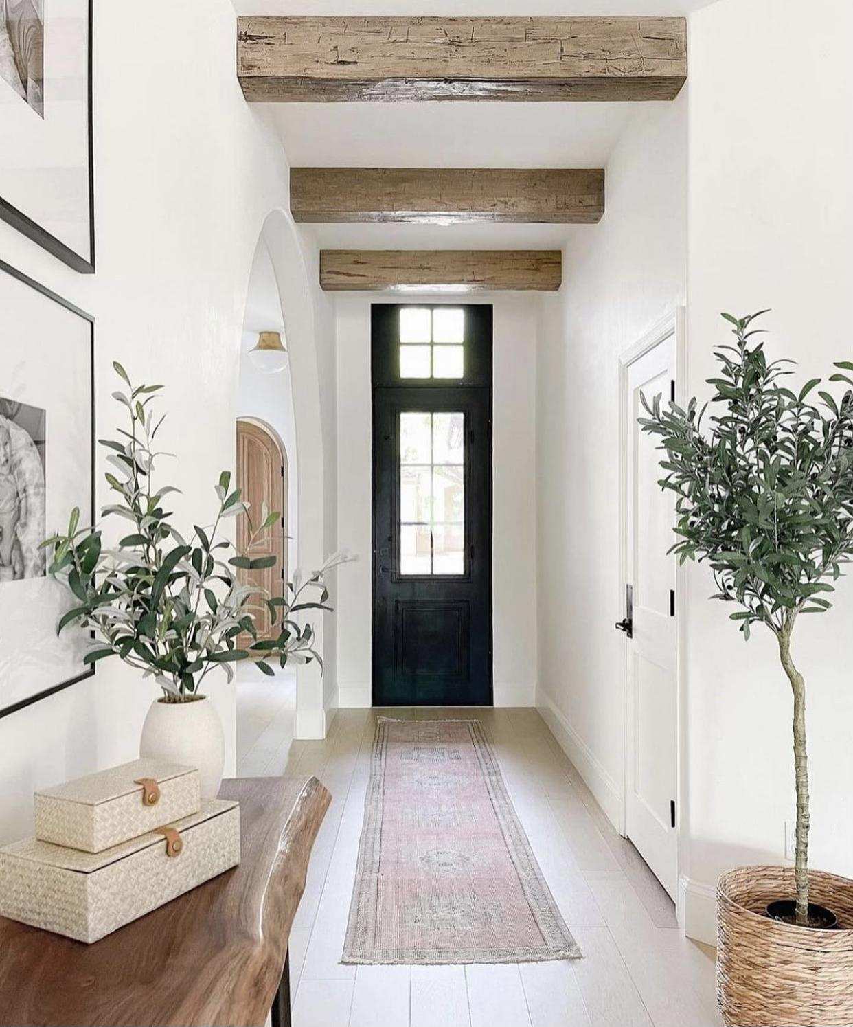 Finished white entryway with detailed wall panels and wood beams